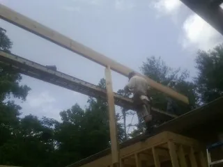 Carpenter setting a ridge beam over a new addition frame — Ice Dam Removal by Roofing Brothers in Grass Valley