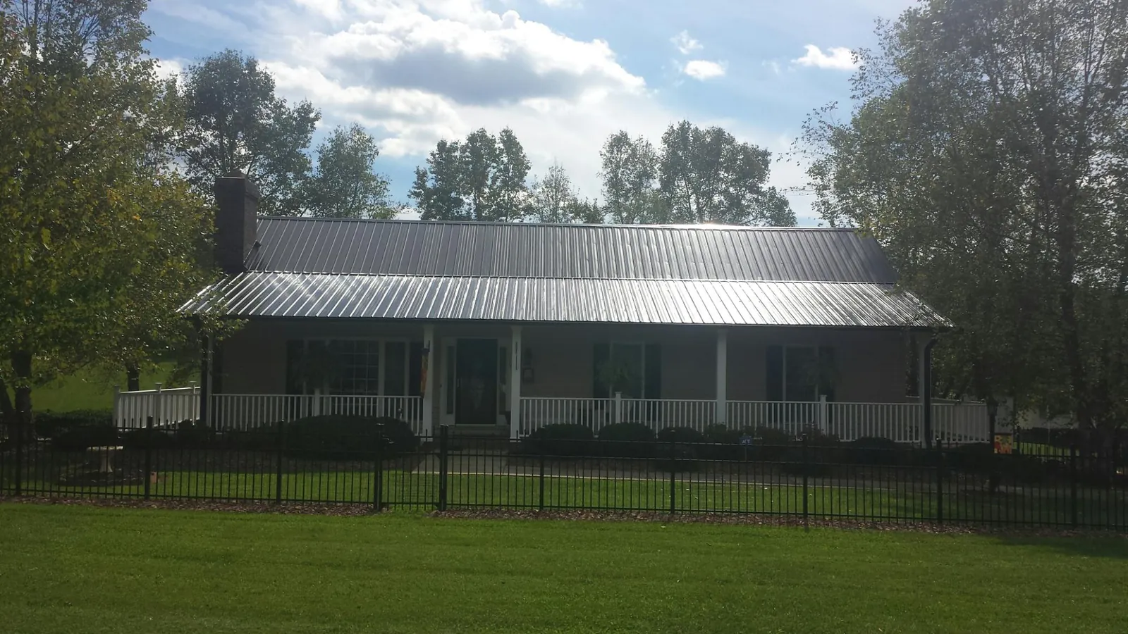 Gray metal roof on a brick ranch with a full width front porch — Gutter Guard Installation work by our crew in Grass Valley